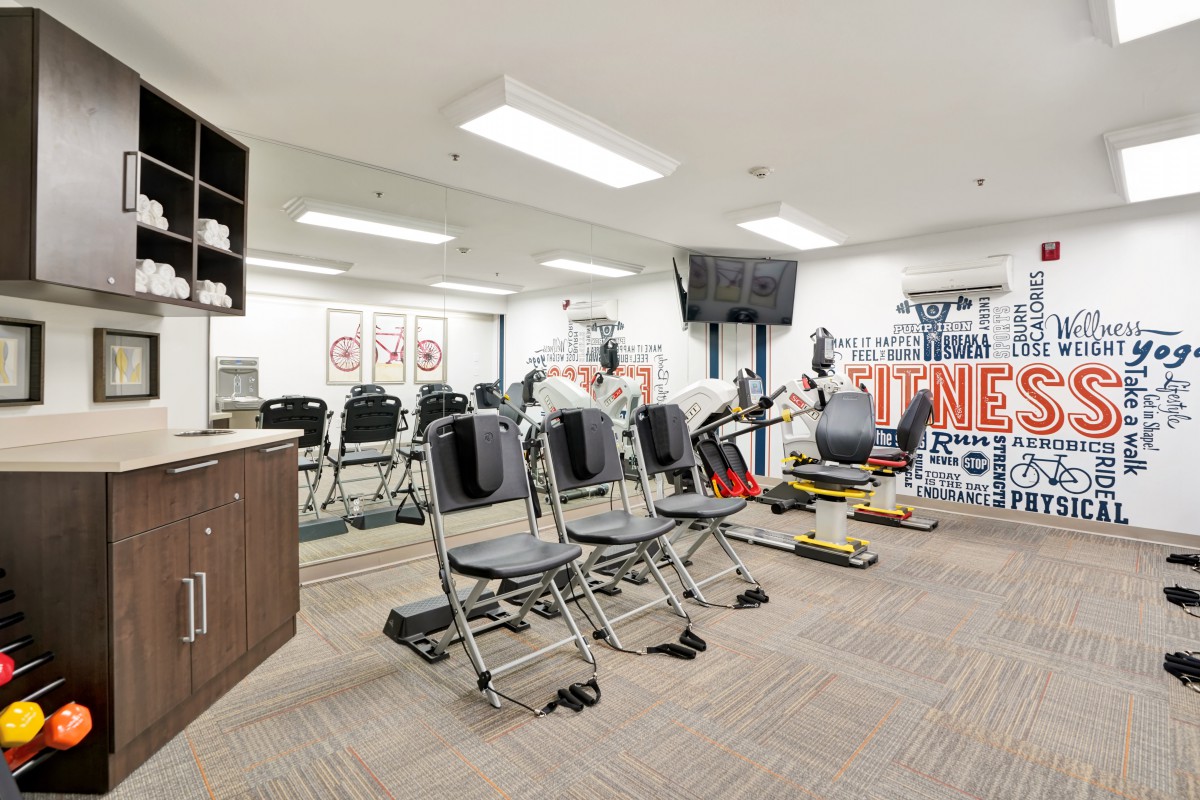 A home gym equipped with exercise machines, chairs, and mirrored walls.