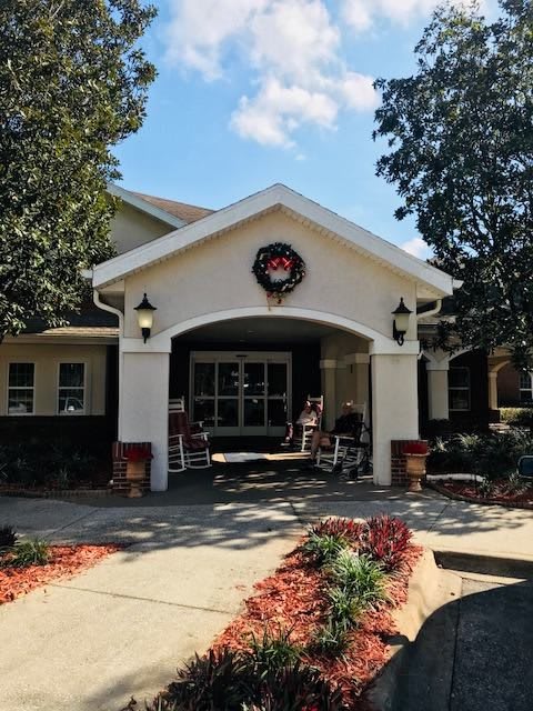 A welcoming house entrance adorned with a holiday wreath, surrounded by neatly landscaped paths.