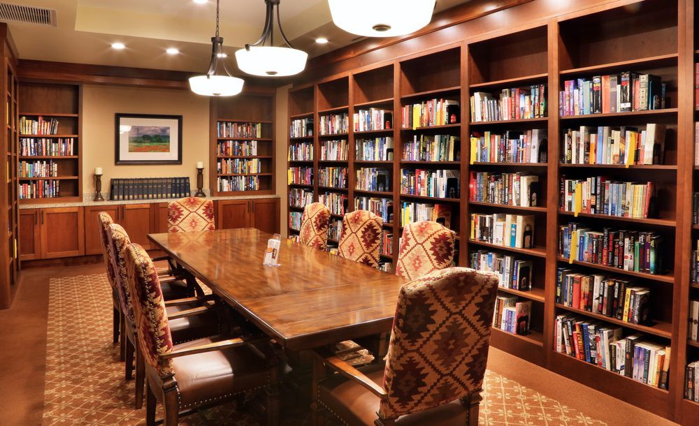 A cozy library conference room with wooden bookshelves and a large table surrounded by chairs.