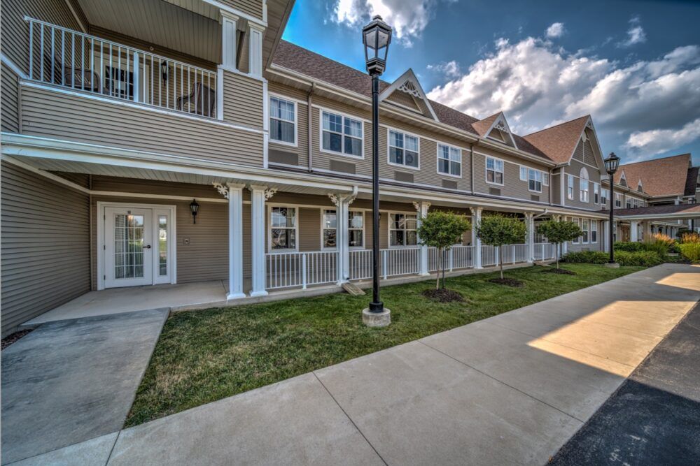 A view of a residential building with porches and landscaped surroundings.