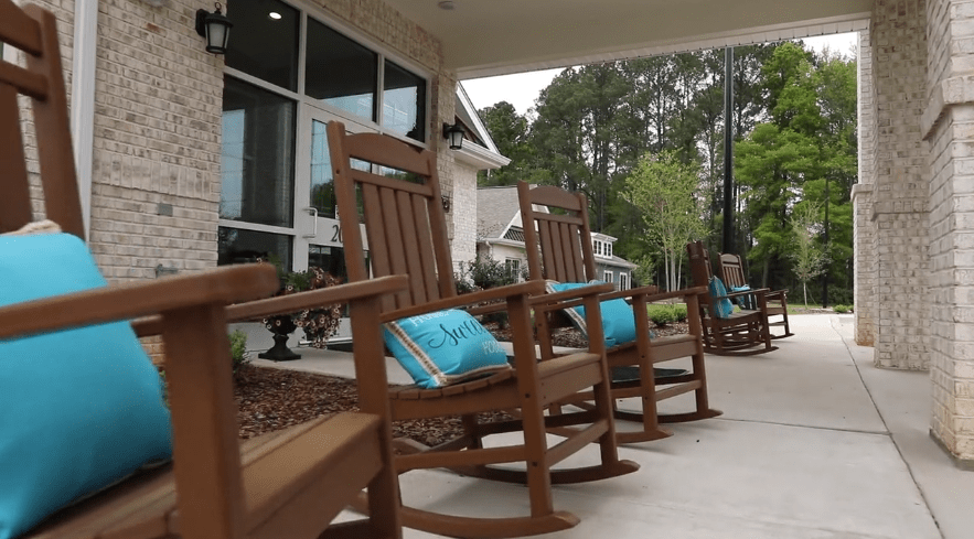 Wooden rocking chairs with blue cushions on a patio.