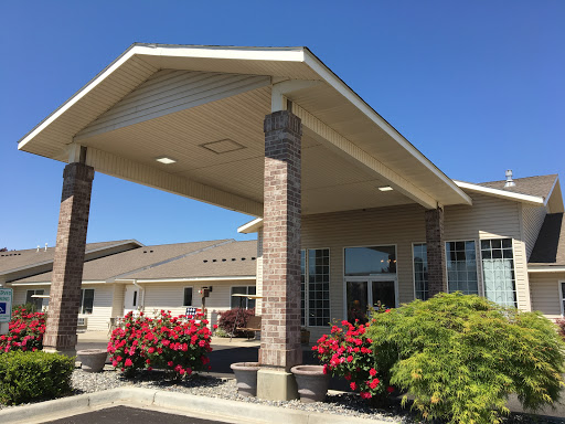 Welcoming entrance of a modern building surrounded by vibrant flowers on a sunny day.