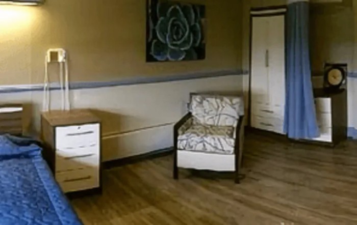A simple room interior with a chair, cabinet, and wall artwork.