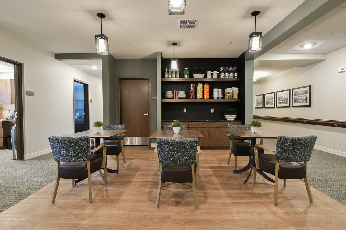 A modern dining area with stylish furniture, decorative shelving, and wood flooring.