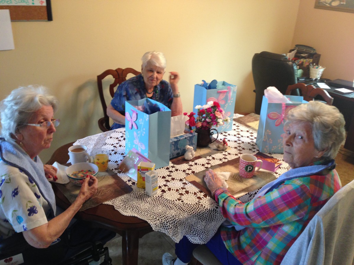 A group of seniors enjoying a gathering at a table with gift bags.