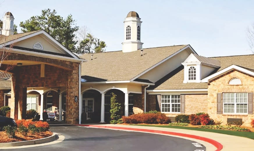 A residential building with a covered entrance and surrounding landscape.