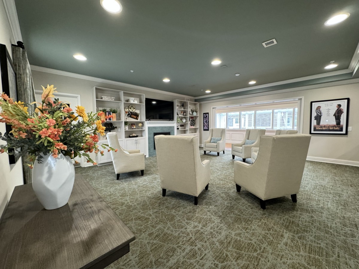 A modern living room with neutral tones, featuring comfortable seating, a fireplace, and built-in bookshelves.