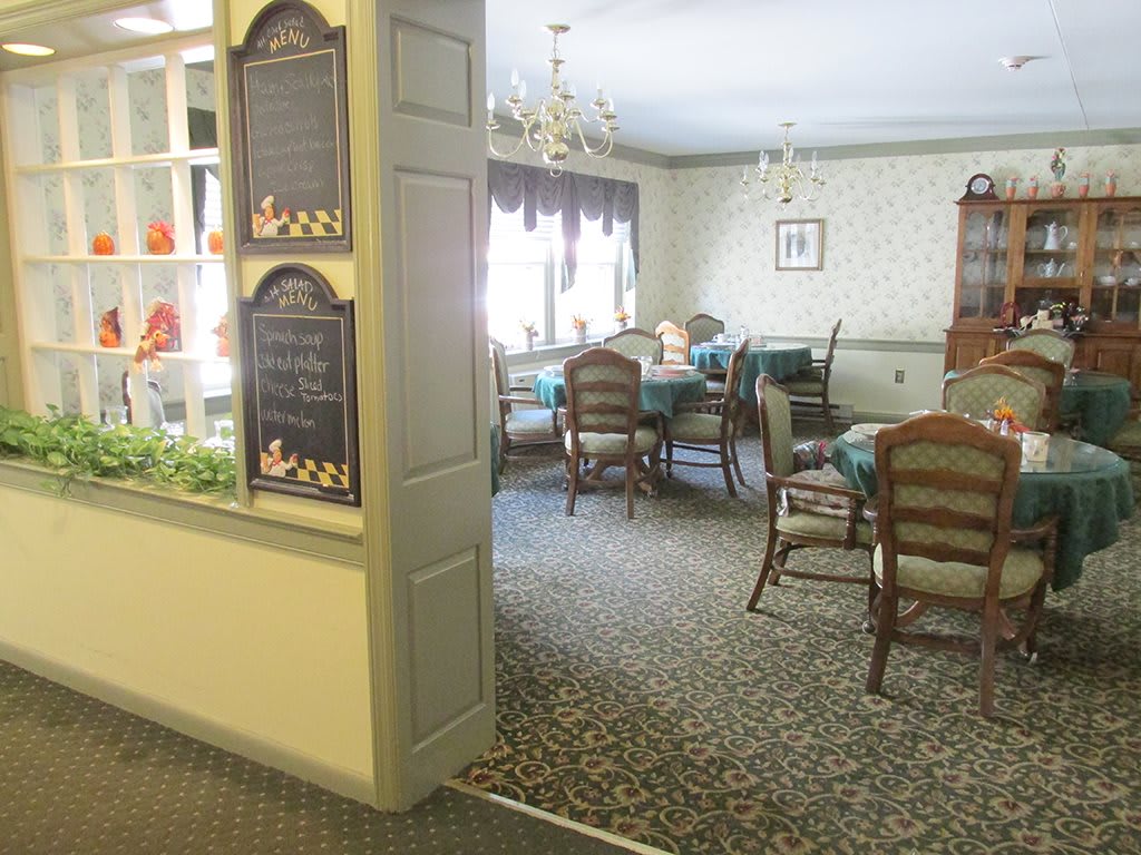 A cozy dining room with elegant chandeliers and neatly arranged tables and chairs.