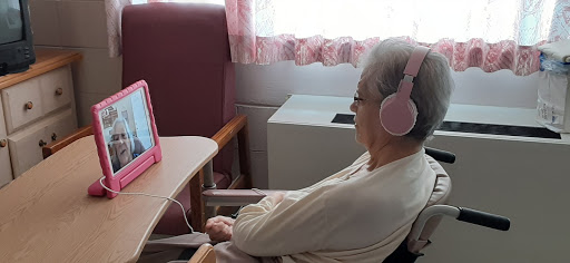 An elderly woman enjoying music on headphones in a comfortable indoor setting.