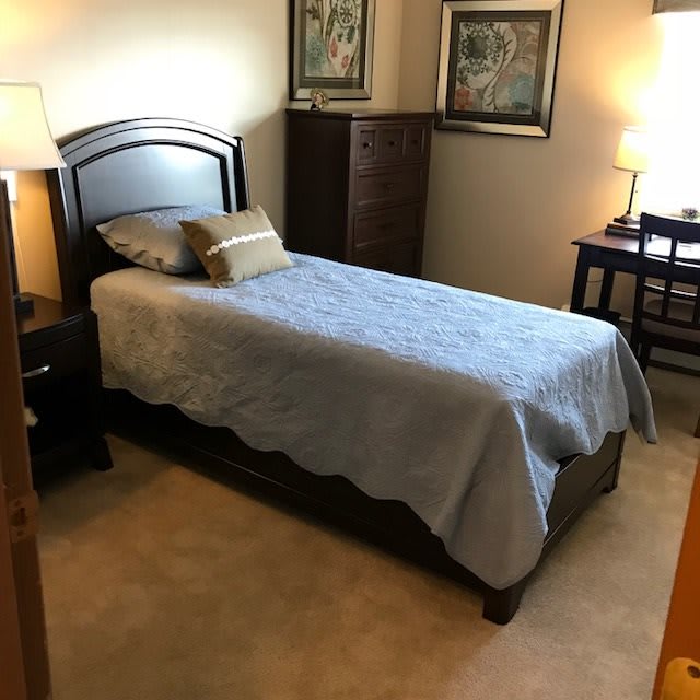 A cozy bedroom with a single bed and warm lighting.