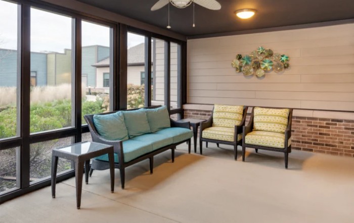 A cozy sunroom with comfortable seating and large windows.