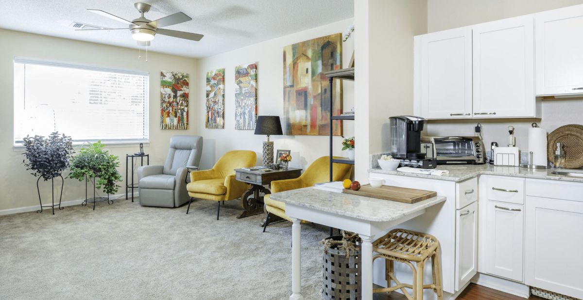 A modern living room with yellow chairs, colorful artwork, and a cozy coffee station.