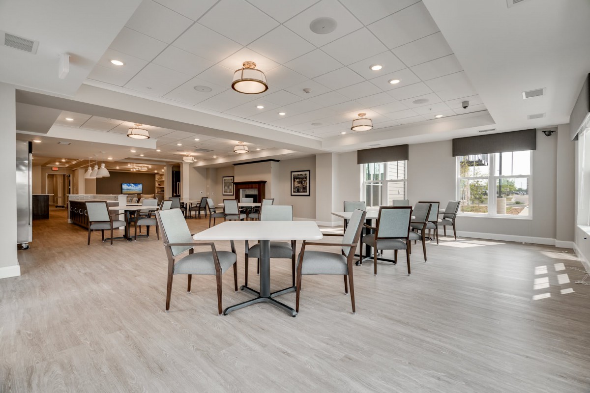 A modern dining area with neatly arranged tables and chairs, featuring elegant lighting.