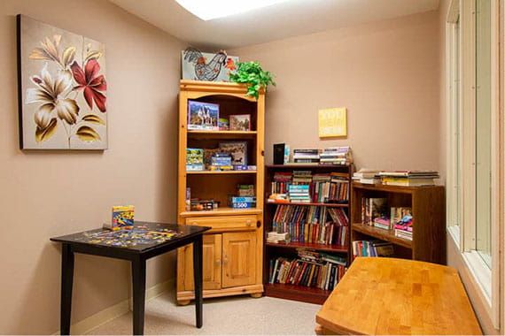 A cozy reading room with wooden bookshelves filled with books and games.