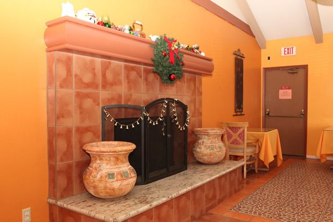 A cozy indoor fireplace adorned with holiday decorations and vintage pots.