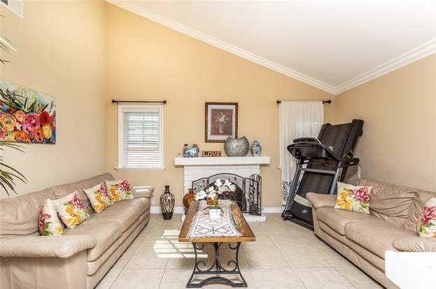 A cozy living room featuring a fireplace, two sofas, and a treadmill.