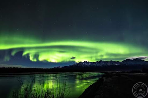 A stunning display of the Northern Lights illuminating the night sky over a tranquil landscape.