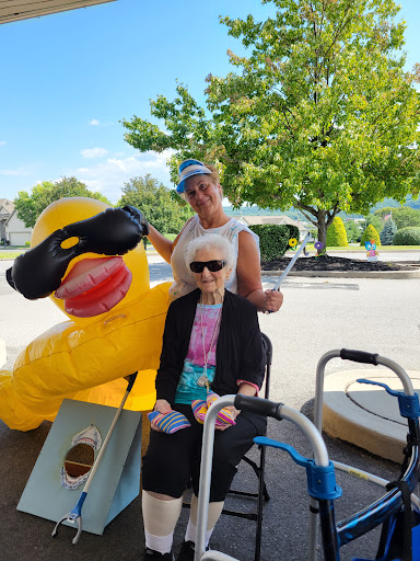 A joyful moment outdoors with an elderly woman and a large inflatable duck.