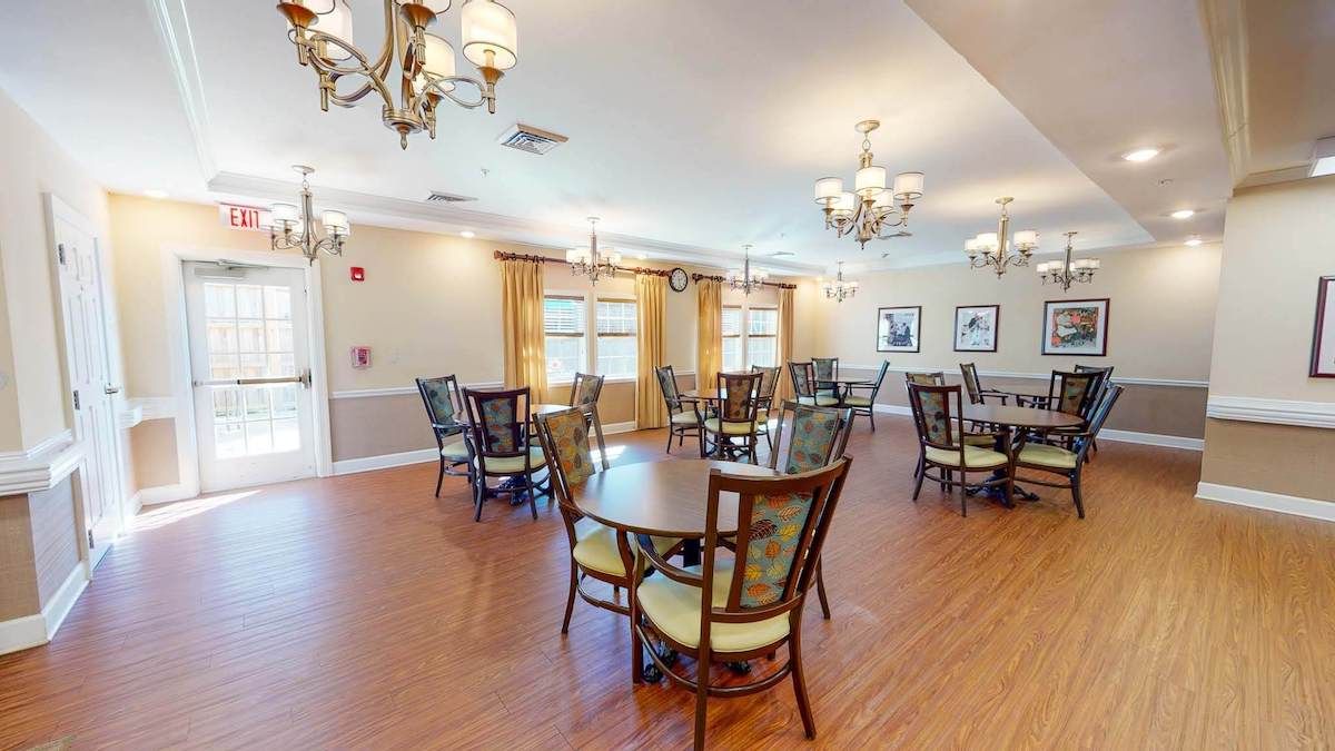 A well-lit dining area with several round tables and elegant chandeliers.