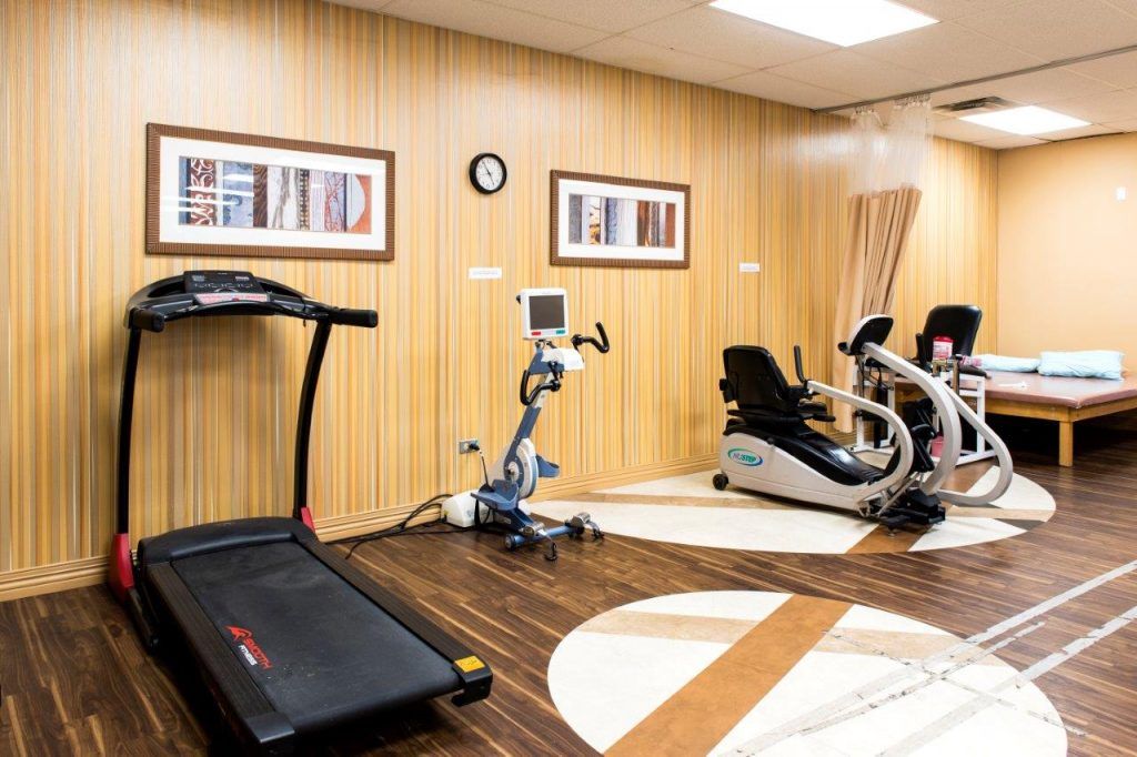 A modern gym with a treadmill, stationary bike, and recumbent bike.