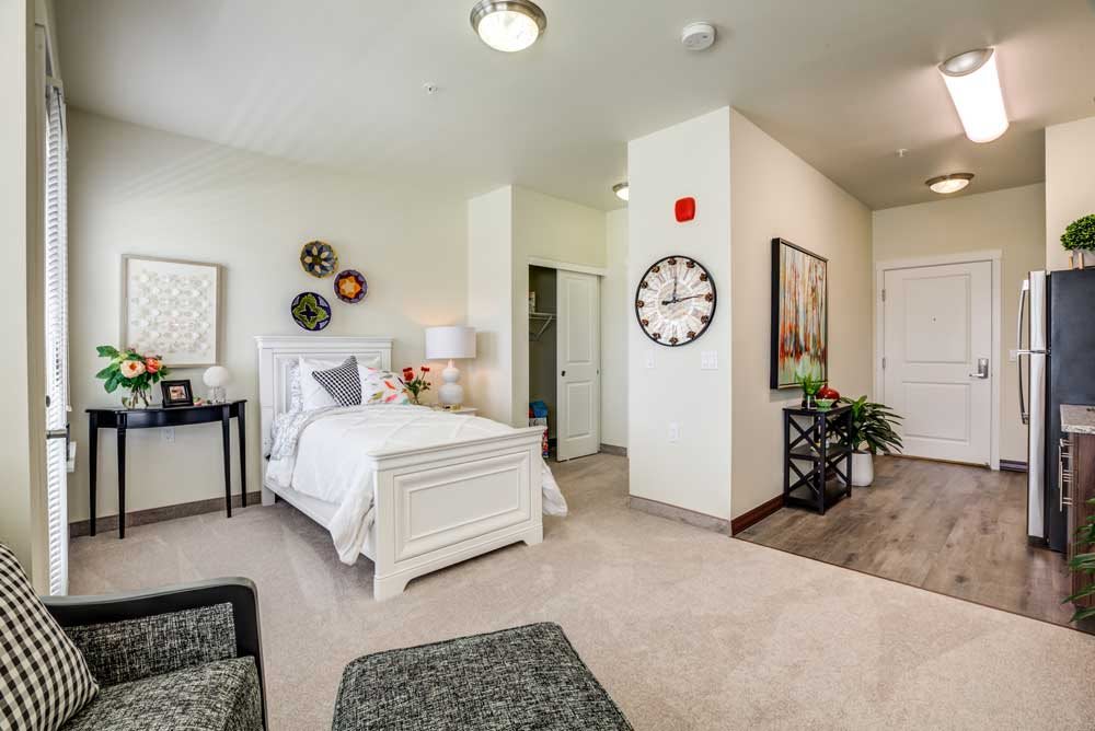 A well-decorated bedroom with a cozy ambiance featuring a bed, artwork, and modern decor elements.
