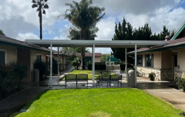A well-maintained outdoor space featuring a green lawn and seating area under a canopy.