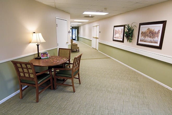 A neat and well-decorated hallway with a table, chairs, and artwork on the walls.