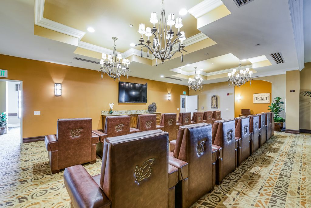 A well-appointed conference room with leather chairs, chandeliers, and a wall-mounted television.