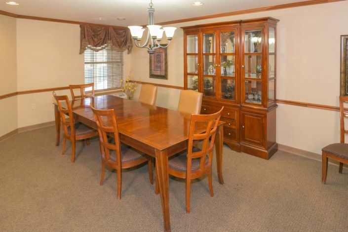 A formal dining room with a wooden table, chairs, and a glass cabinet.