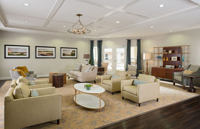 A spacious living room with elegant furnishings, featuring sofas, armchairs, a coffee table, and a chandelier.