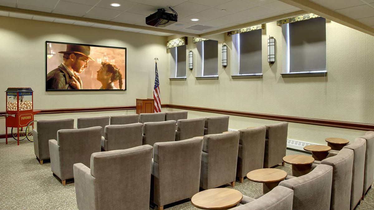 A small conference room with rows of seating and a projector screen at the front.