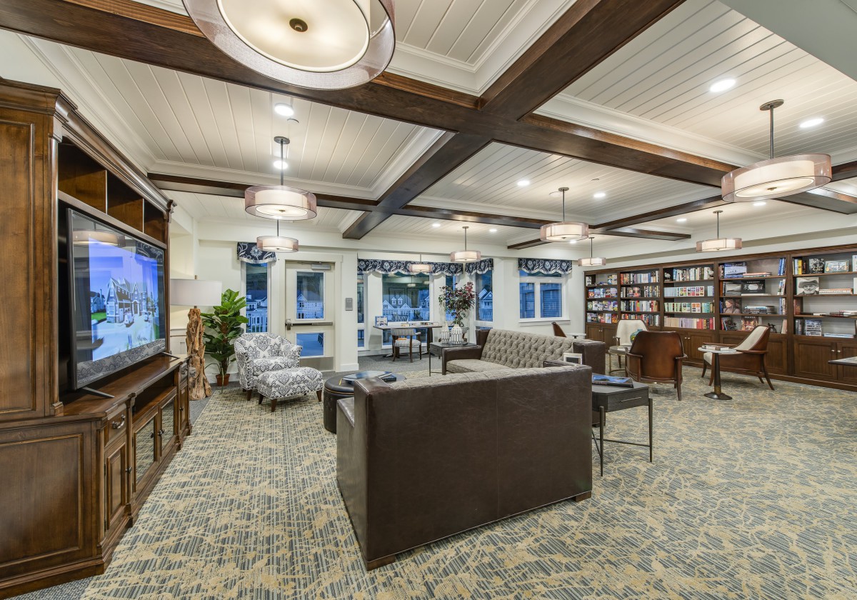 A modern living room with a cozy seating area, television, and a small library.