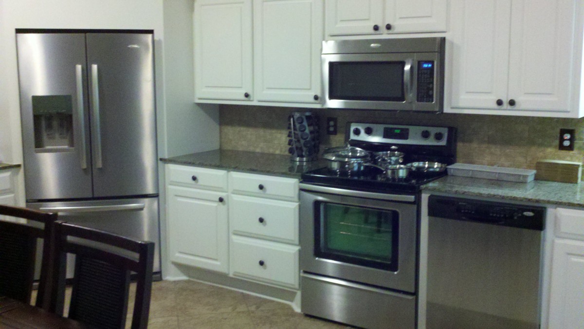 A modern kitchen featuring stainless steel appliances and white cabinetry.