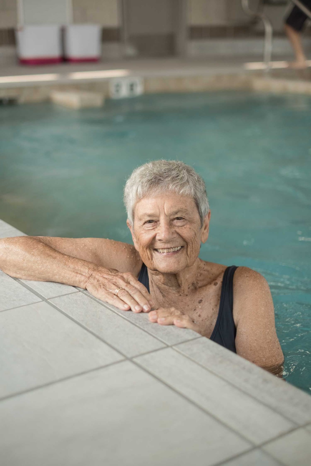An elderly woman enjoying a swim in the pool.