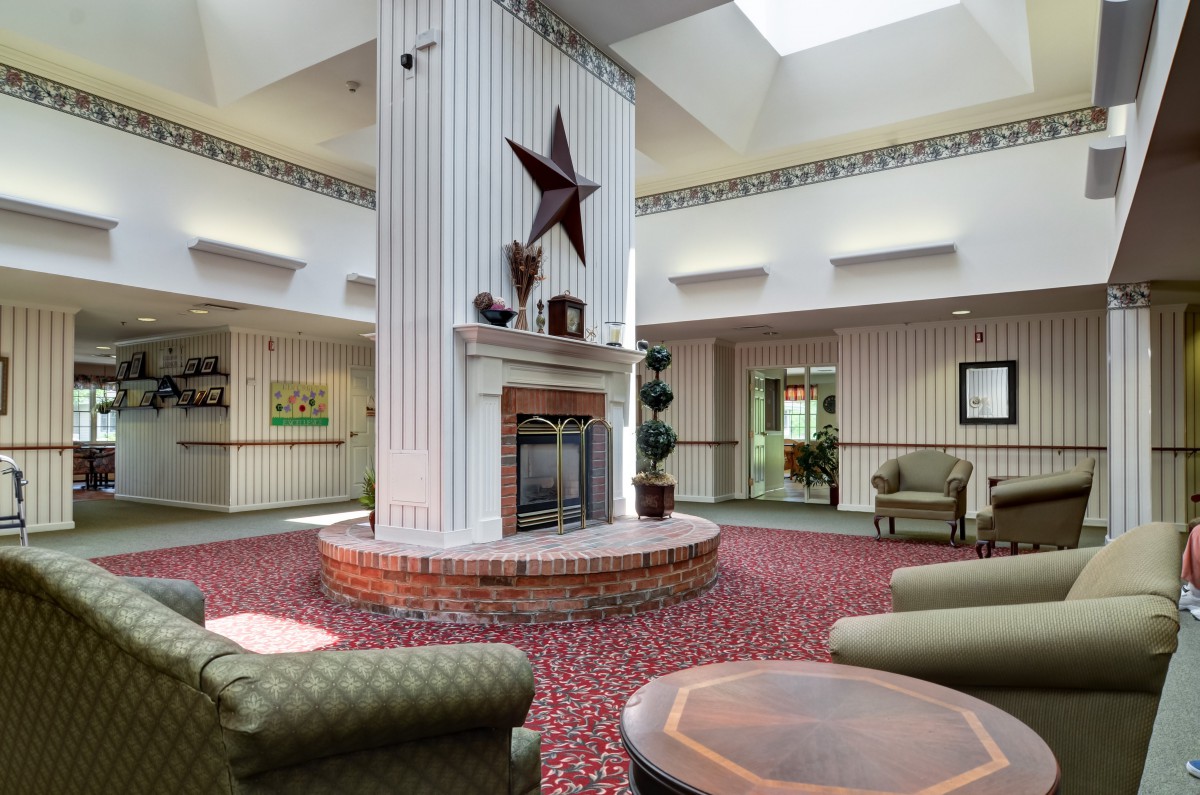 A cozy lobby interior with a central fireplace and seating area under a skylight.