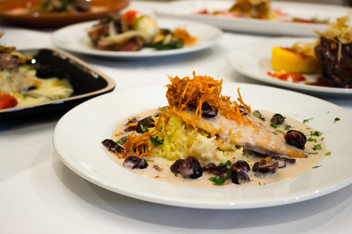 A beautifully plated gourmet dish featuring tender fish with a garnish of crispy vegetables and a creamy sauce.