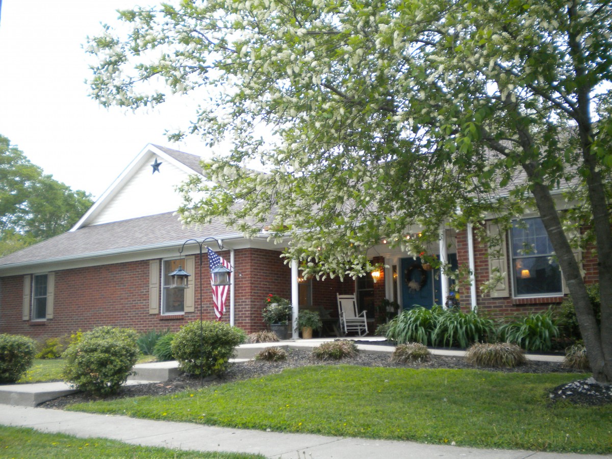 A suburban brick house with a porch and landscaped front yard.