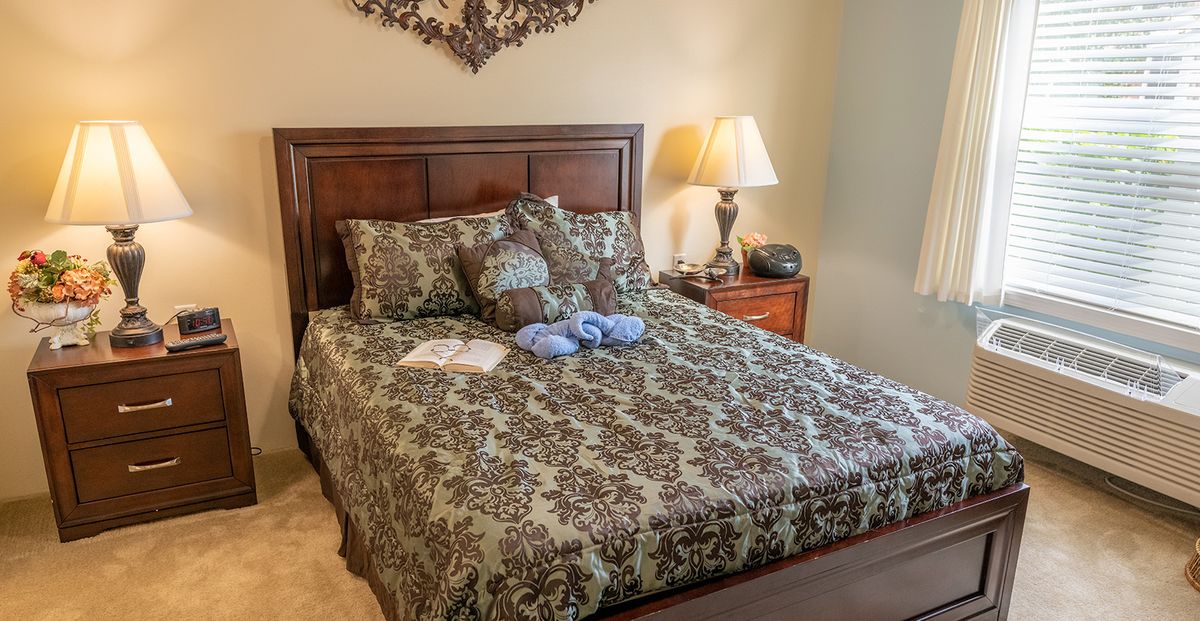 A cozy bedroom featuring a bed with patterned bedding, bedside tables, and a lamp.