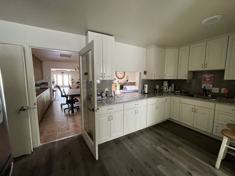 A modern kitchen with white cabinets and open access to a dining area.