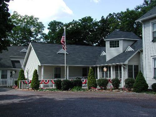 A residential building with an American flag in the front and trees in the background.