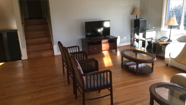 A cozy living room with a TV, chairs, and a coffee table on hardwood flooring.