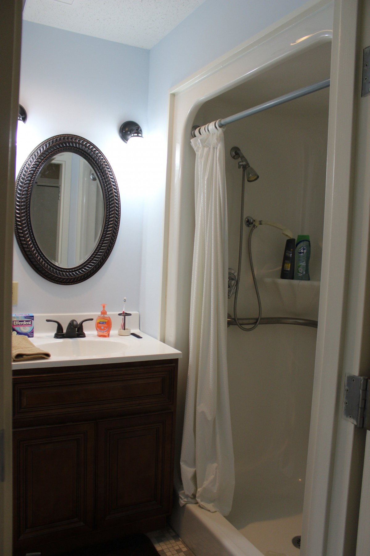 A bathroom with a sink, mirror, and shower area.
