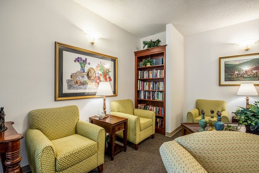 A cozy living room with comfortable chairs, a small bookshelf, and a decorative painting on the wall.