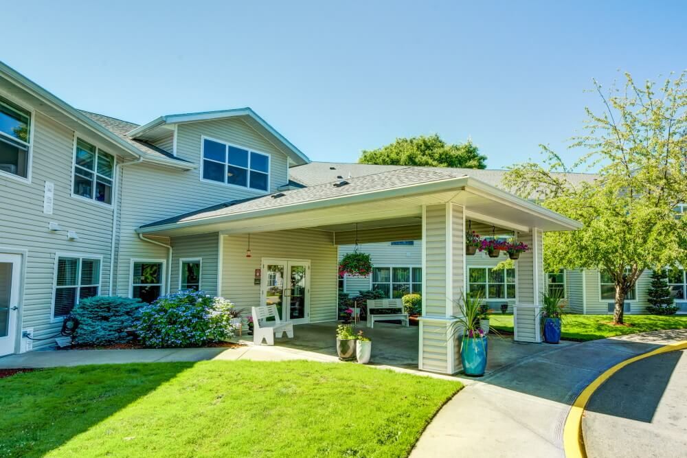 A welcoming residential building with a front porch and well-maintained lawn on a sunny day.