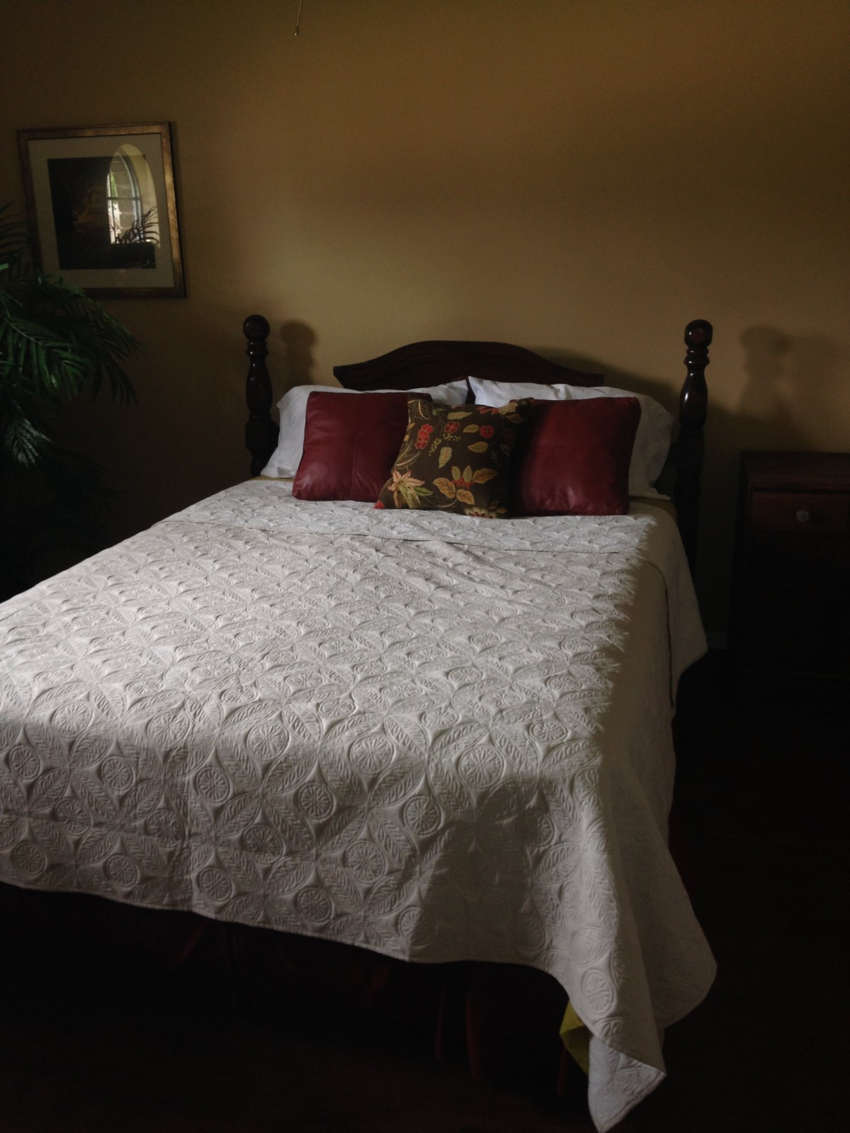 A cozy bedroom with a neatly made bed featuring decorative pillows and a quilt.