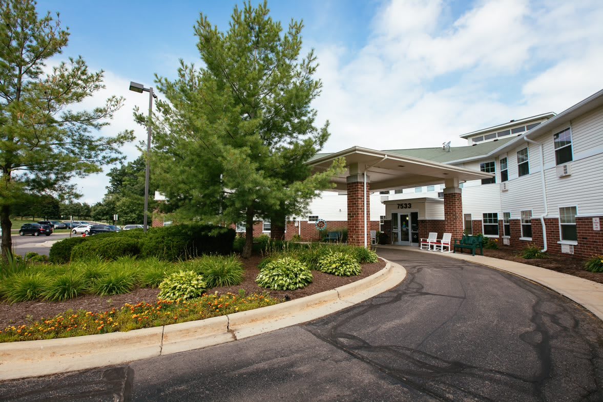 A building entrance with a driveway and landscaped surroundings.