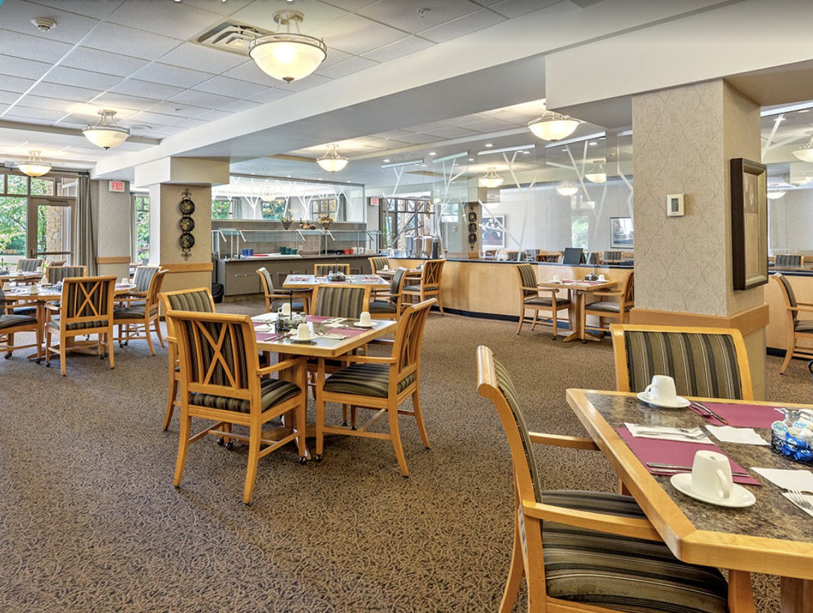 An empty dining area with neatly set tables and chairs, featuring warm lighting.