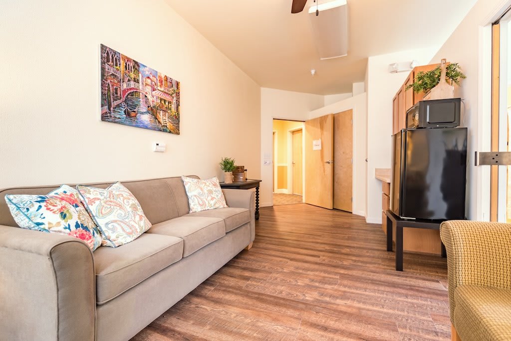 A modern living room with a comfortable sofa, hardwood flooring, and stylish artwork on the wall.
