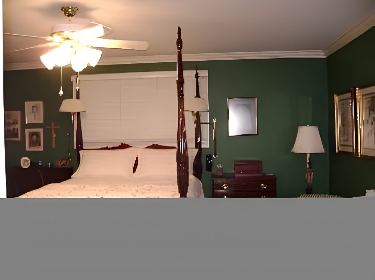 A traditional bedroom with a four-poster bed, green walls, and classic furnishings.
