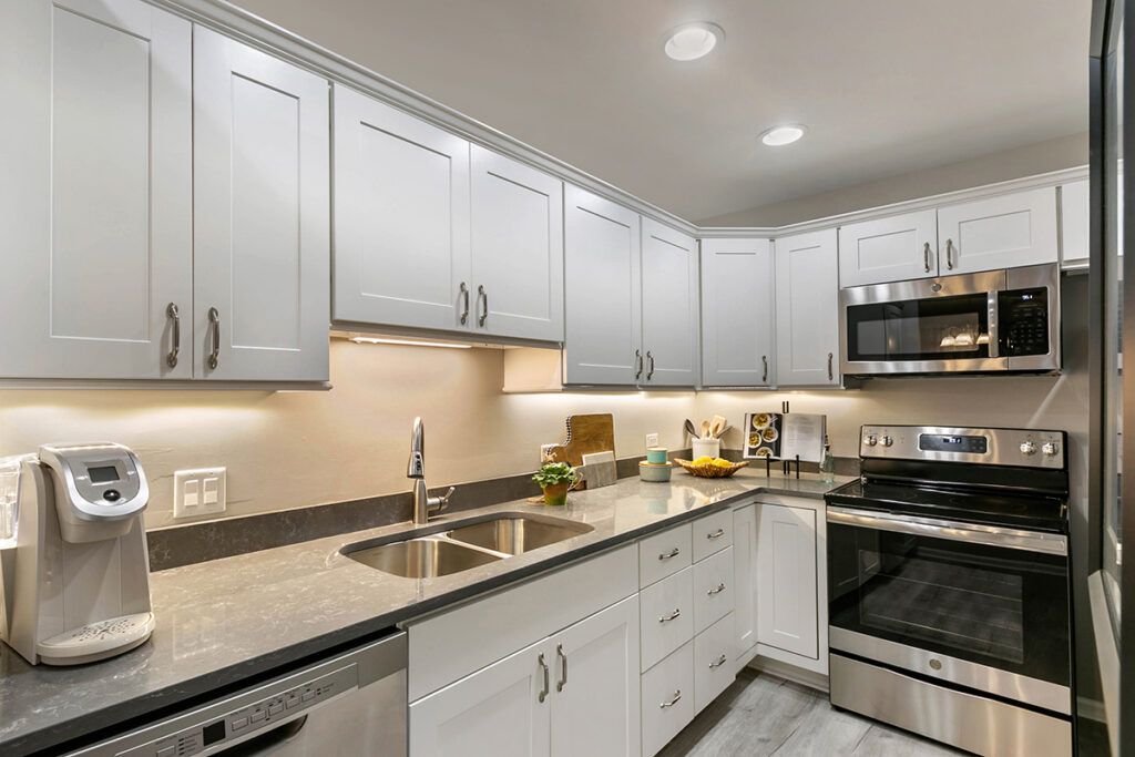 A modern kitchen with white cabinets and stainless steel appliances.